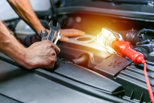 car repair shop concept photo. motor repairing close up. mechanic hands hold wrenches on the background of a car engine