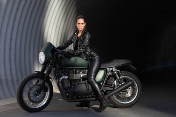 Naklejka na ściany i meble Portrait of young woman on a black motorcycle