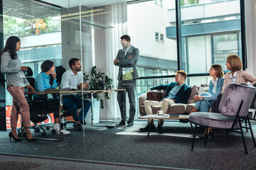 Office colleagues having discussion during meeting in conference room. Group of men and women in modern office.