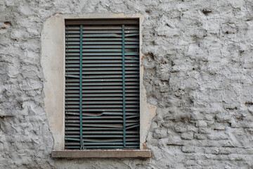 Fototapeta na wymiar Brick stone wall with old and damaged green roll up jalousie front of the window frame, no person