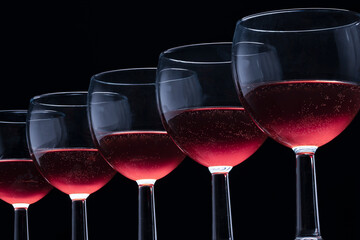 Red wine in crystal small glasses in a row on a black background alcoholic drinks.