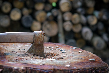 An ax on old stump and firewood backdrop as background