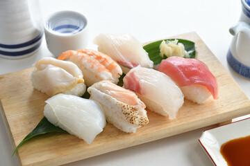 Sushi Set nigiri sashimi and on wooden serving board with soy sauce and Japanese Sake over white background-Jananese Food