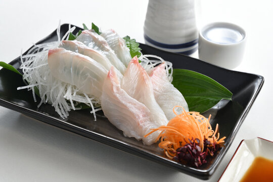 Raw red sea bream sashimi on black plate with soy sauce and Japanese Sake-Japanese food