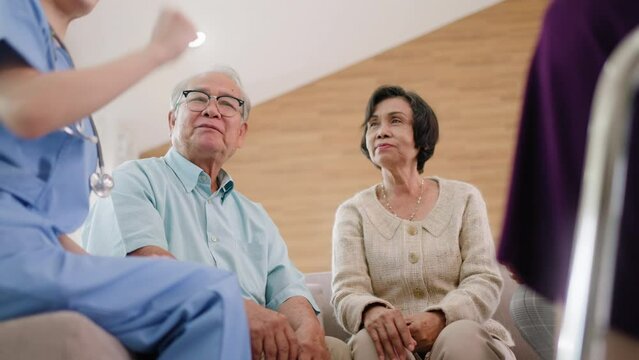 Group of asian senior people listening to young nurse.Psychological support group for elderly therapy session in a community centre. Group therapy in session sitting in a circle in a nursing home.