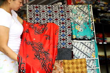 Indonesian batik cloth, Asian women choose batik motifs at batik cloth shops and umkm product in...