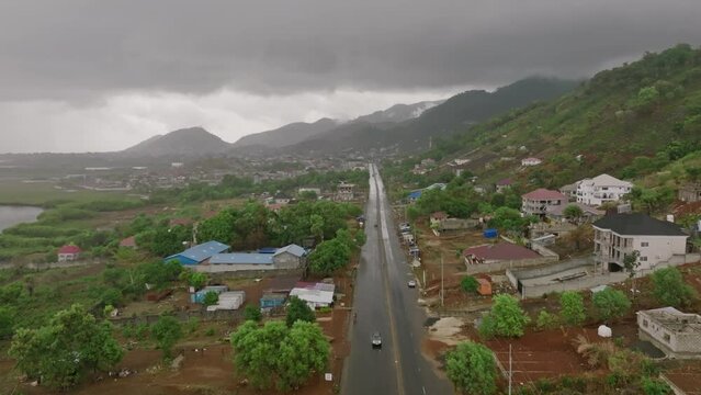 Aerial footage flying over a road on the coast of Sierra Leone right after the rain and everything is glistening.