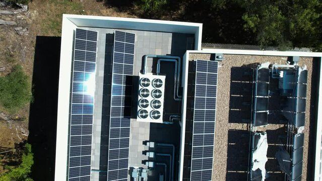 Aerial view above air condition units and photovoltaic cells on a roof - top down, drone shot