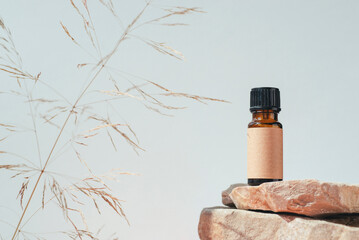Amber bottles with craft label and essential oil on stone podium. Grey background. Beauty concept...