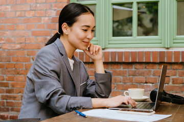 Asian young woman working with laptop while sitting in cafe