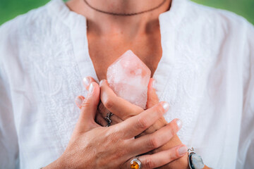 Self-worth meditation concept. Hands holding a rose quartz crystal, meditating, improving a sense of self-worth, focusing on being good and worthy of love and belonging - obrazy, fototapety, plakaty