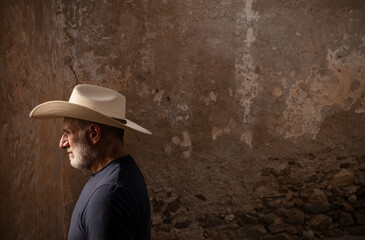 Side view of adult man in cowboy hat against wall