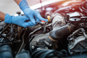Close-up of the hands of a car mechanic who checks the oil in the car engine.