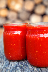 Ready tomato paste in a jar on the table. Tomato ketchup sauce in a glass bowl. The concept of sauces, seasonings, preservation.
