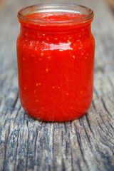 Ready tomato paste in a jar on the table. Tomato ketchup sauce in a glass bowl. The concept of sauces, seasonings, preservation.