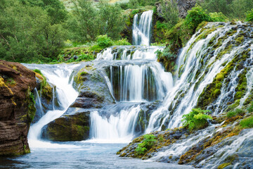 Gjain waterfall flowing with lush jungle in Pjorsardalur valley on summer at South of Iceland