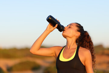 Runner drinking from bottle at sunset