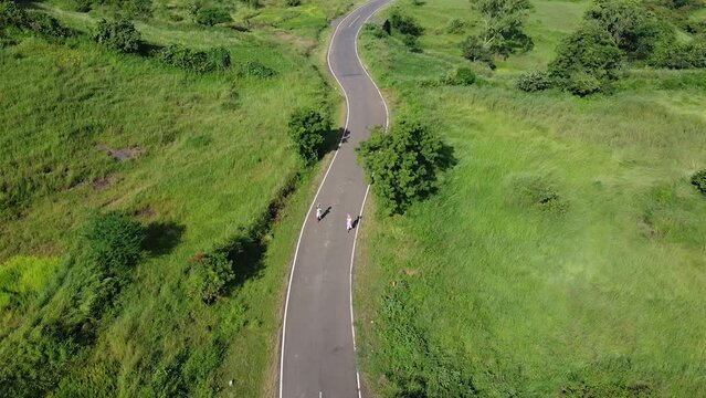 People Walking On Winding Road Through Lush Meadow In Trimbakeshwar, Nashik, India. aerial pullback