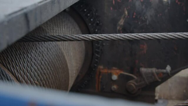 large rusty machine gear turns slowly letting go an iron cable