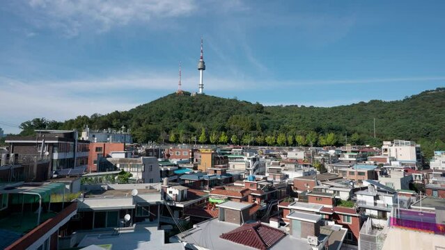 Aerial view of  Yongsan Haebangchon village rooftops and Seoul Tower at Namsan mountain over blue sky  - establishing shot static