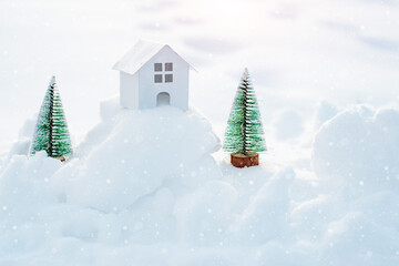 Decorative white house with a spruce tree in the snow in the sunlight outdoors, free space