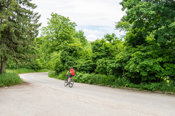 A man quickly rides a bicycle against the backdrop of a green forest