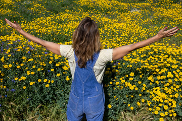 Carefree mature woman with arms outstretched standing in front of flowering plants at park