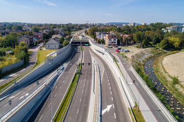 New city highway Trasa Lagiewnicka in Krakow, Poland, with tunnels, slip ways, cycle path and pavement for pedestrians. Regulated Wilga river decorated with stones