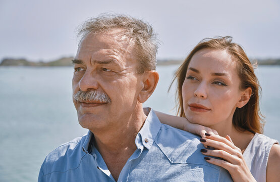Thoughtful young woman standing with father next to sea