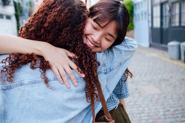 Smiling young woman hugging friend on street