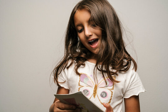 Cute Girl Reading Book Against Gray Background