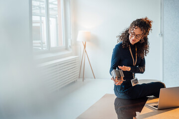 Smiling young engineer analyzing semiconductor sitting on desk in office