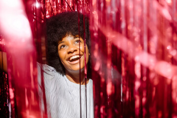 Cheerful woman amidst red tinsels enjoying party