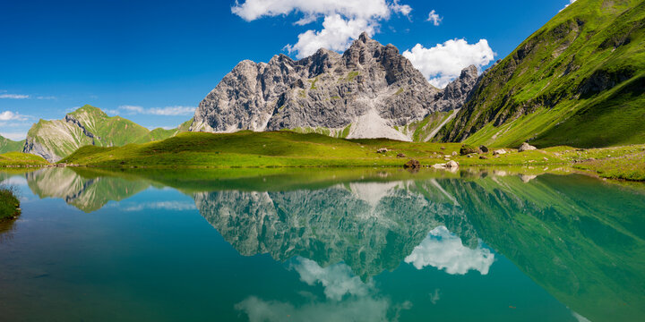 Reflection of Allgau Alps in lake Eissee on sunny day