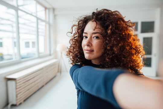 Young woman with curly hair taking selfie