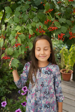 Smiling girl with eyes closed standing under Viburnum tree