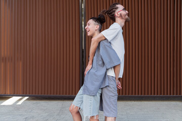 Couple standing back to back in front of wall