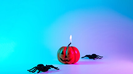 Halloween decoration. Scary spooky pumpkin, black night spider on night neon helloween background. Minimalistic background for autumn holidays. Space for text.