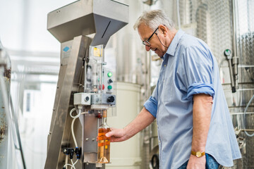 Man filling wine from storage tank in winery.