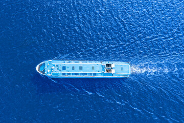 Small passenger ferry boat floats in sea waters, a view from a height exactly from above.