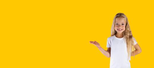 Cheerful girl in a white t-shirt with outstretched hand isolated on a yellow background. Banner, horizontal orientation, copy space.