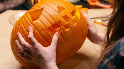 Preparing pumpkin for Halloween. Woman sitting and cleaning carved halloween Jack O Lantern pumpkin at home for her family. - 529983451