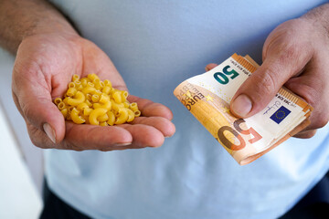 Obraz premium Close-up of the hands of a man holding a macaroni and euro bills in his hands.The concept of rising food prices, the global economic crisis.