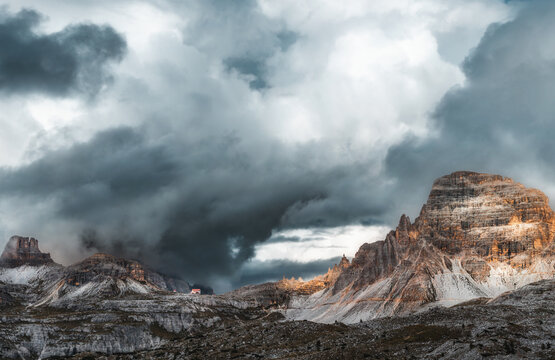 Mystical beautiful mountain landscape with a house on top of a mountain and church with thunder clouds and fog in cloudy weather. Tre Cime park in Dolomites, Italy. Italian alps