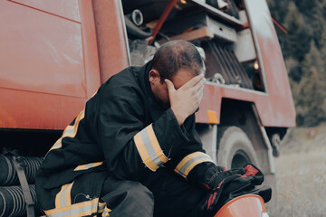 depressed and tired firefighter near fire truck. 