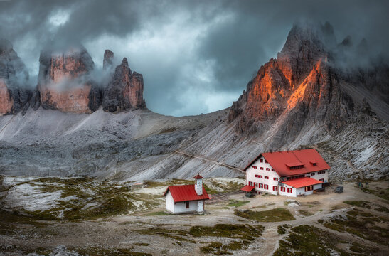 Mystical beautiful landscape with rocky mountains, house and beautiful church at dusk, Italian alps. Tre Cime park in Dolomites, Italy