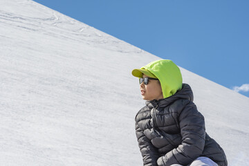 A boy sits on an observation deck against the backdrop of the Caucasus Mountains