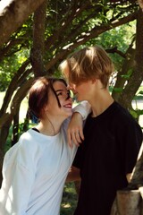 A young couple of teenagers are happy together and want love. First kiss. Girl in a cap