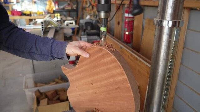 Luthier Drilling Hole in Custom Guitar Body for Jack Installment at Workshop Using Drill Press