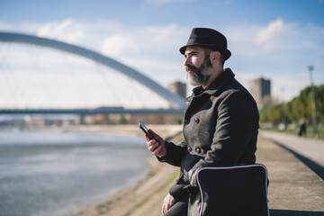 Obraz premium Businessman is sitting outdoor in the city and using smartphone.